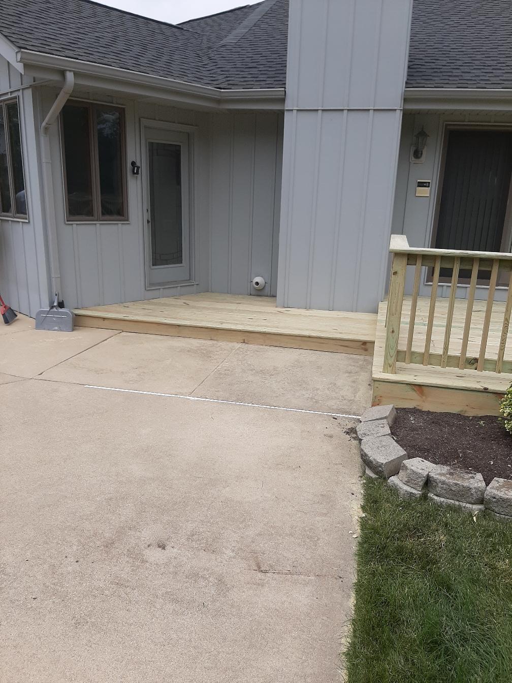 Low-profile residential pressure-treated wood deck entry and walkway installed next to a concrete patio by Precision Exterior Inc.