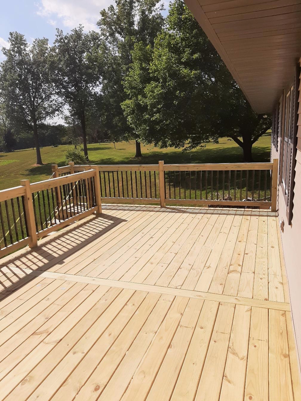 Custom residential wood deck with a hybrid safety railing featuring wood posts and black metal spindles, built by Precision Exterior Inc.
