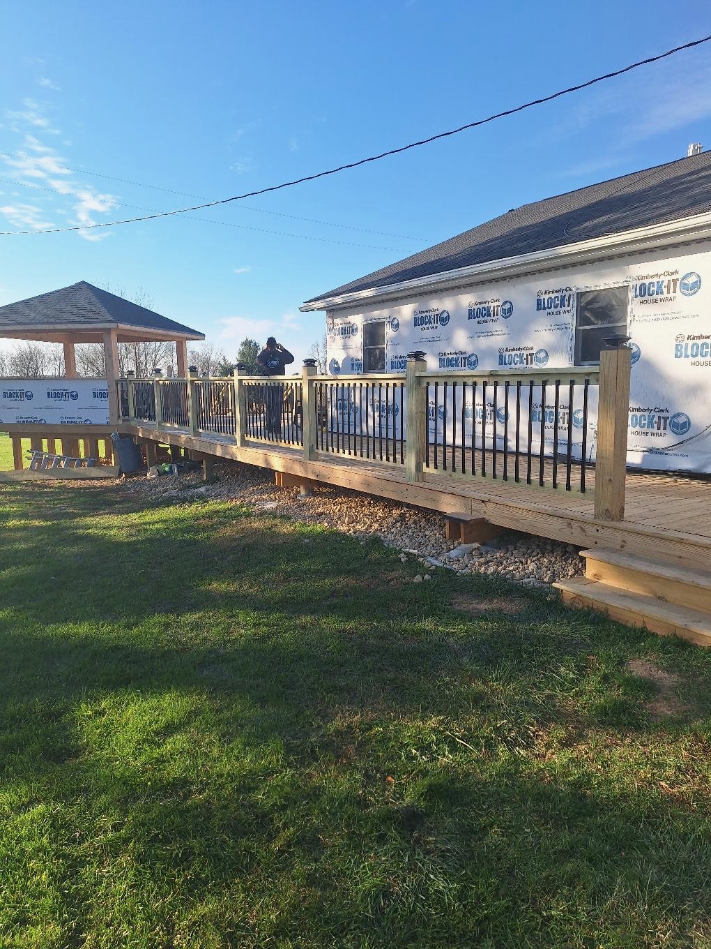 Extensive backyard wood deck construction project with an attached gazebo and black metal balustrade railings by Precision Exterior Inc.