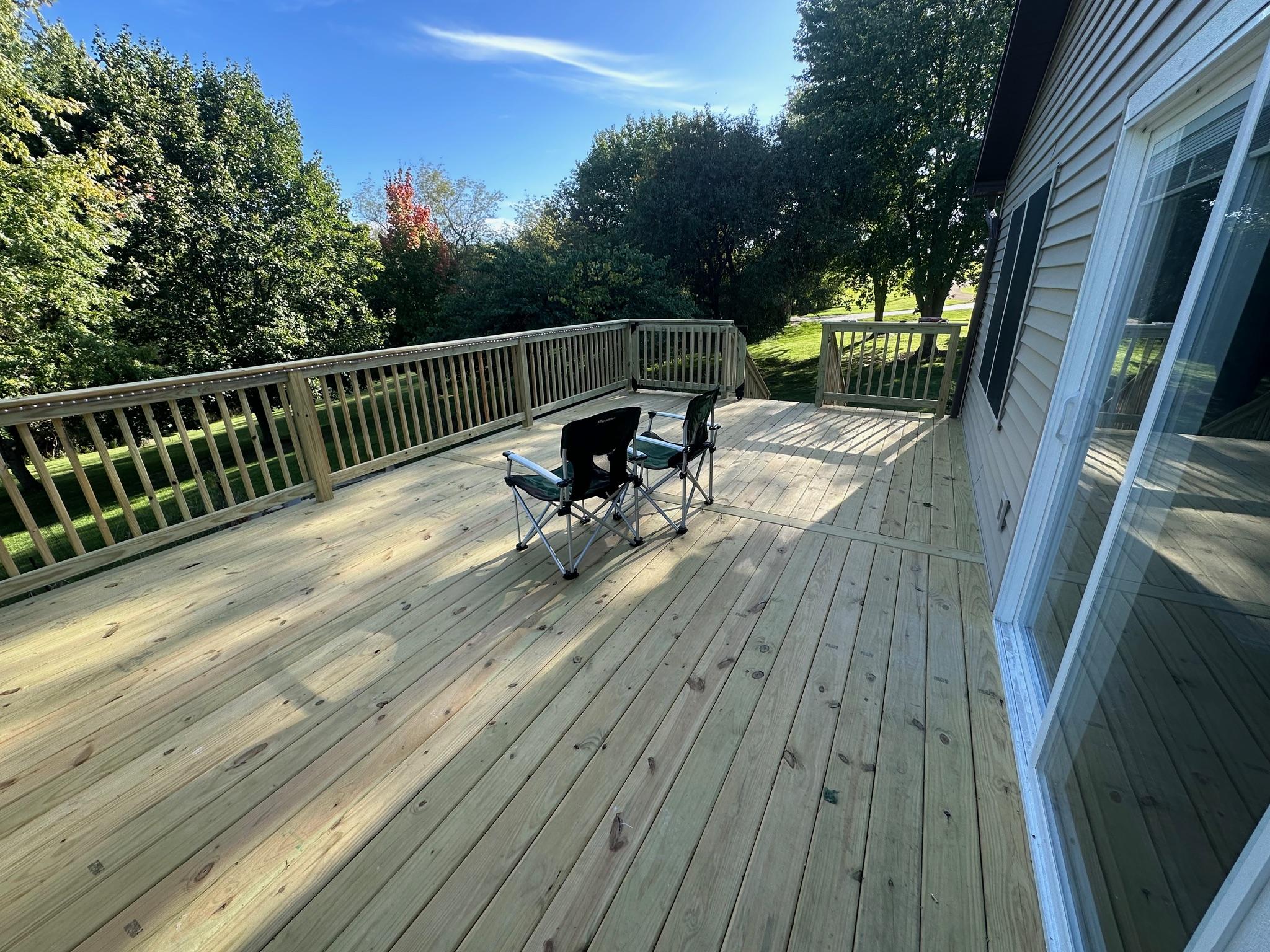 Expansive custom pressure-treated wood backyard deck with matching railings built by Precision Exterior Inc. in Lena, IL.