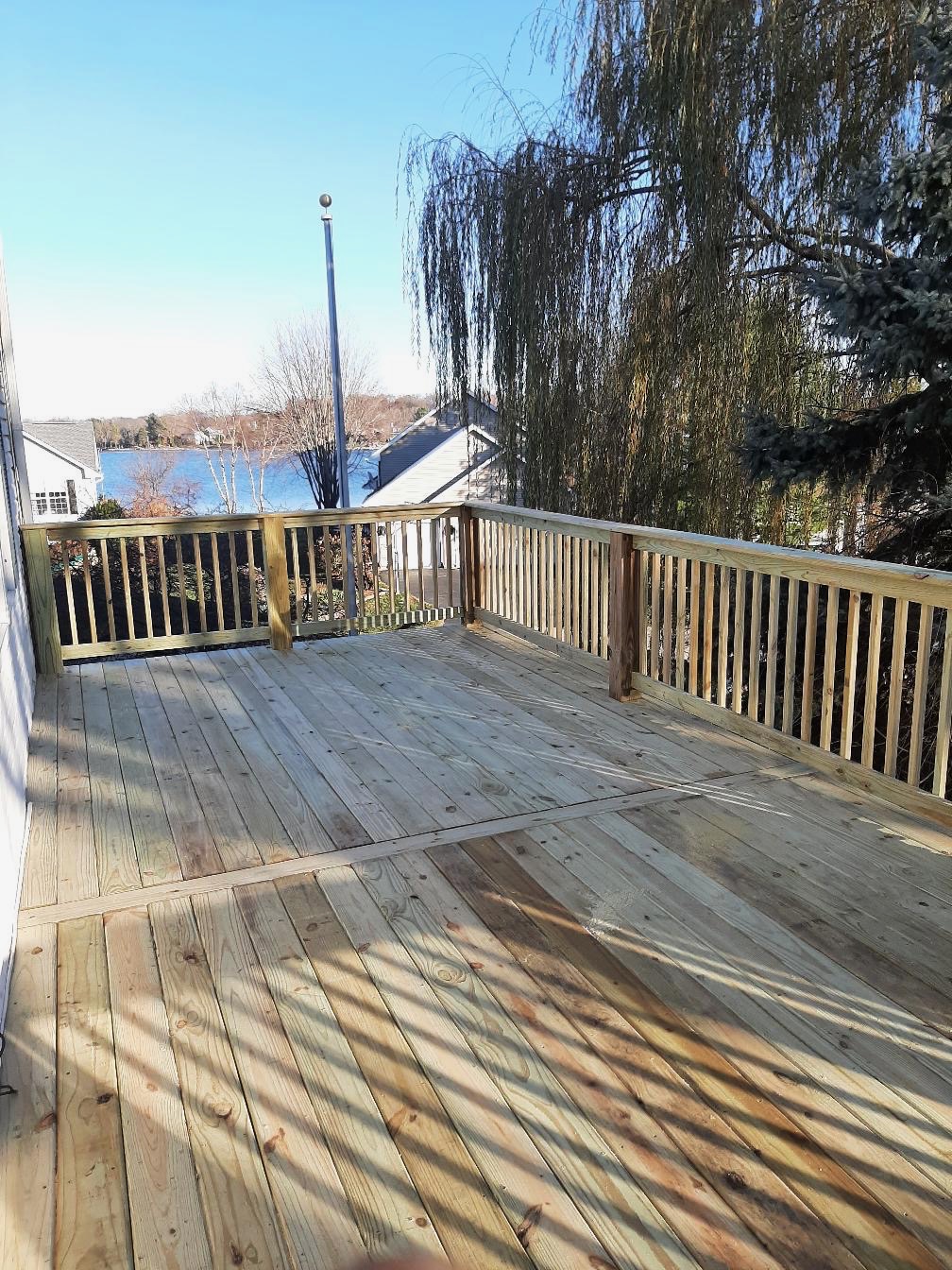 Newly installed elevated residential wood deck with wood safety railings overlooking a lakefront view by Precision Exterior Inc.