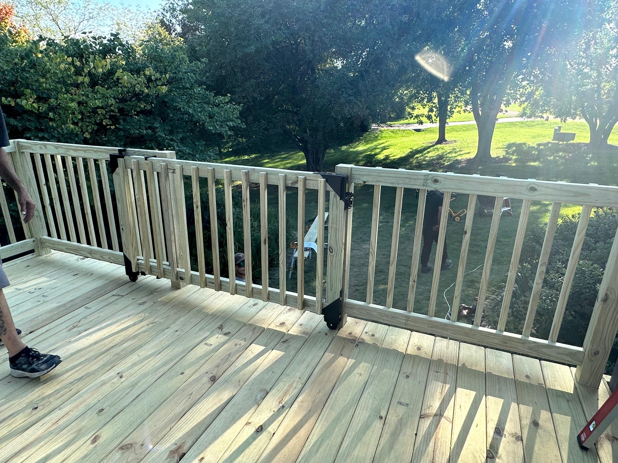 Custom pressure-treated wood deck installation showcasing an integrated wooden safety gate with railings by Precision Exterior Inc.