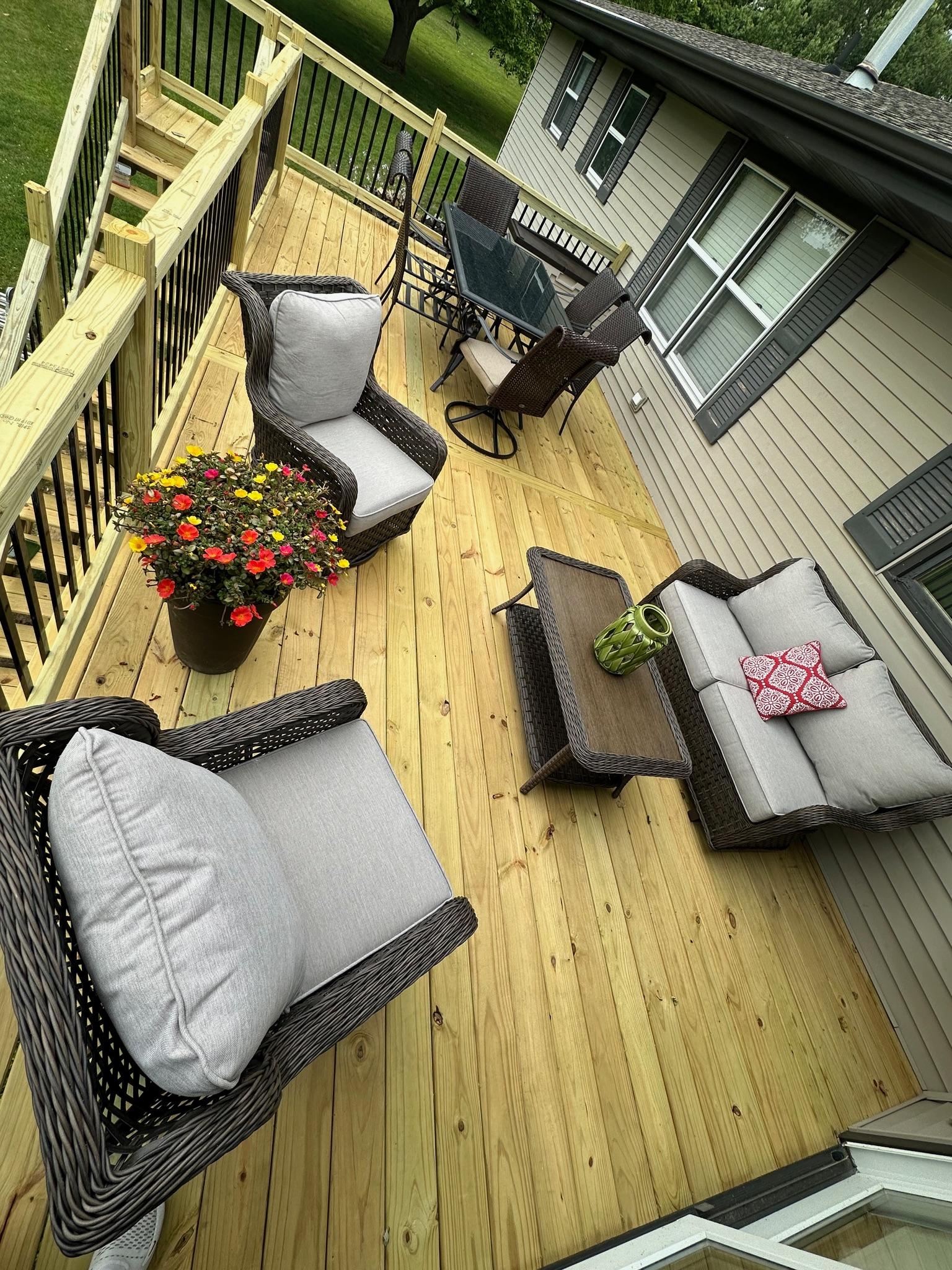 Premium custom wood deck installation with sleek black metal spindles and comfortable outdoor patio furniture, built by Precision Exterior Inc. in Lena, IL.