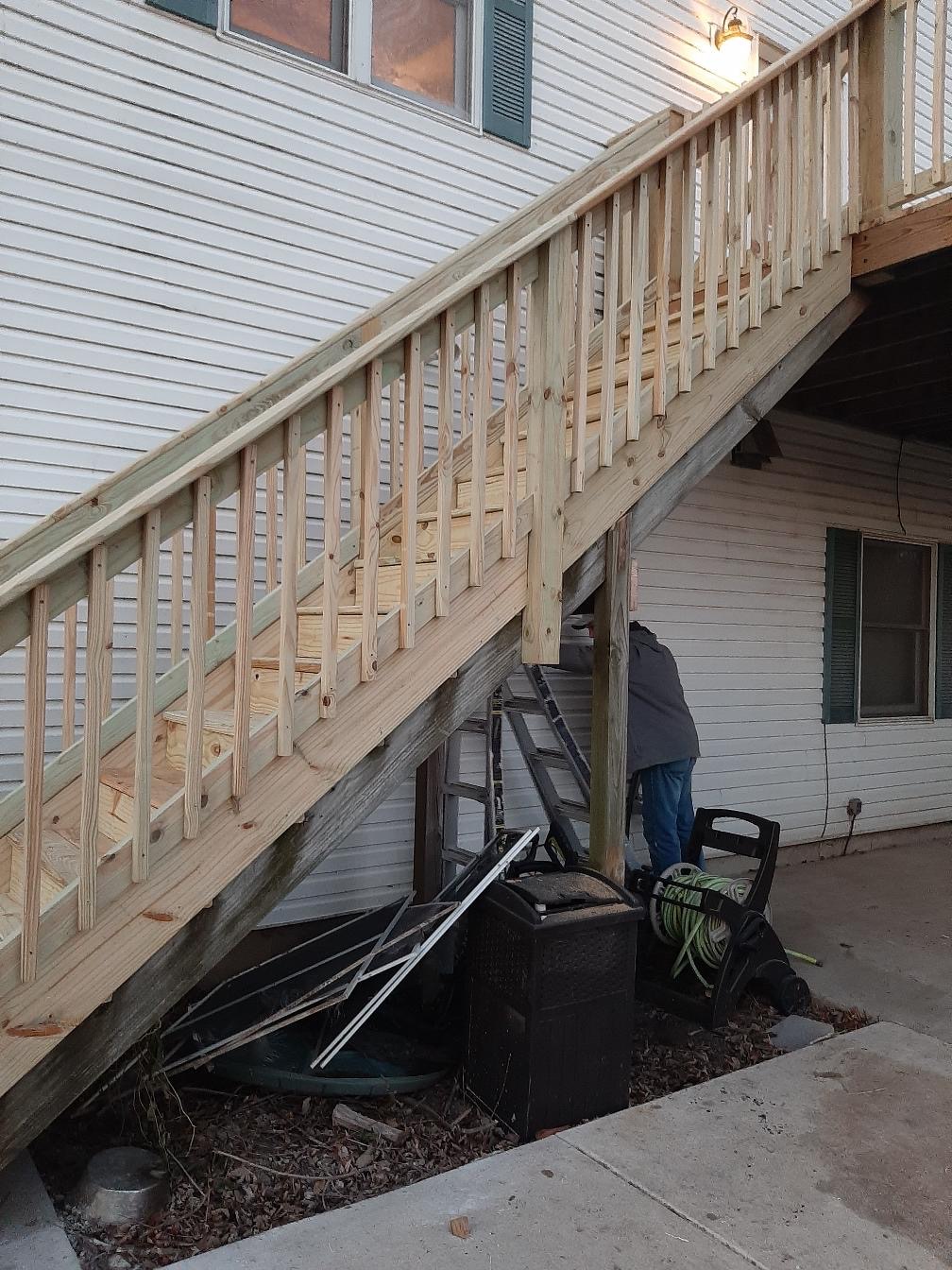 Custom pressure-treated wood deck staircase with wooden safety railings under construction by Precision Exterior Inc.