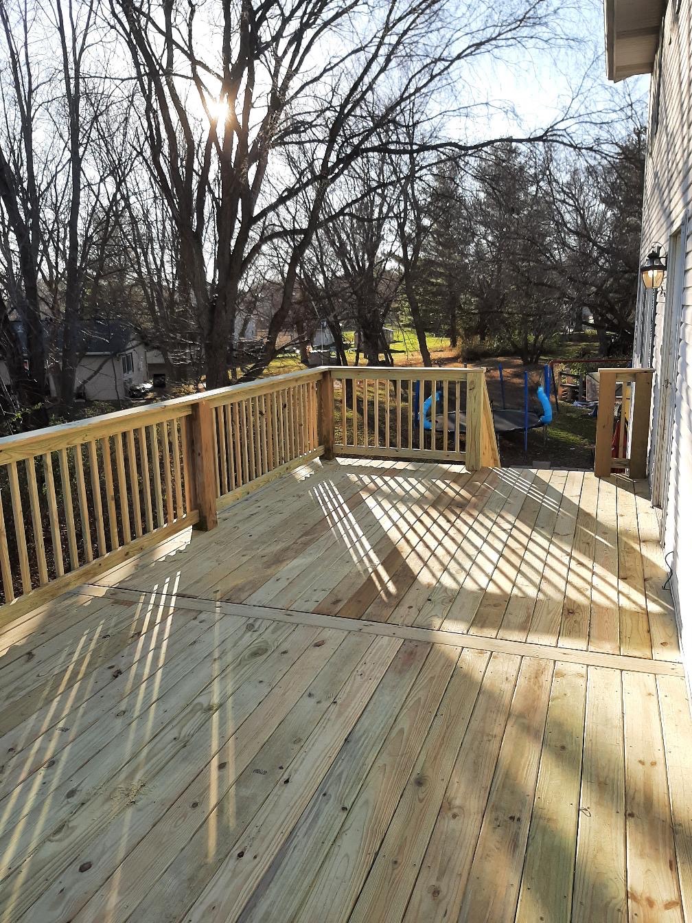 New elevated backyard pressure-treated wood deck with wooden safety railings built by Precision Exterior Inc.