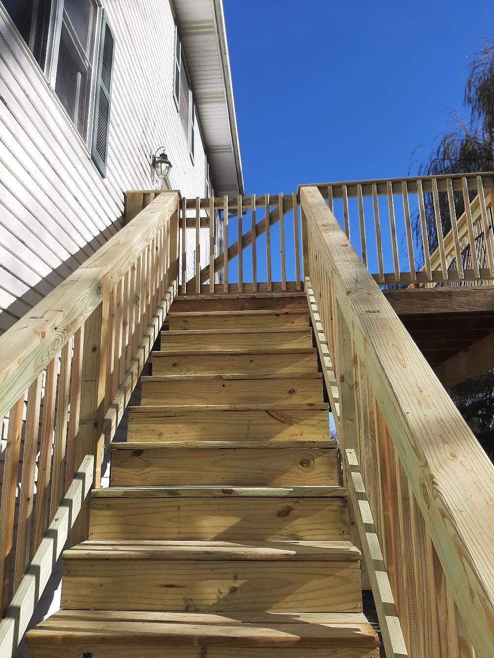 Custom pressure-treated wood deck staircase and matching top safety gate installed on a residential house by Precision Exterior Inc.