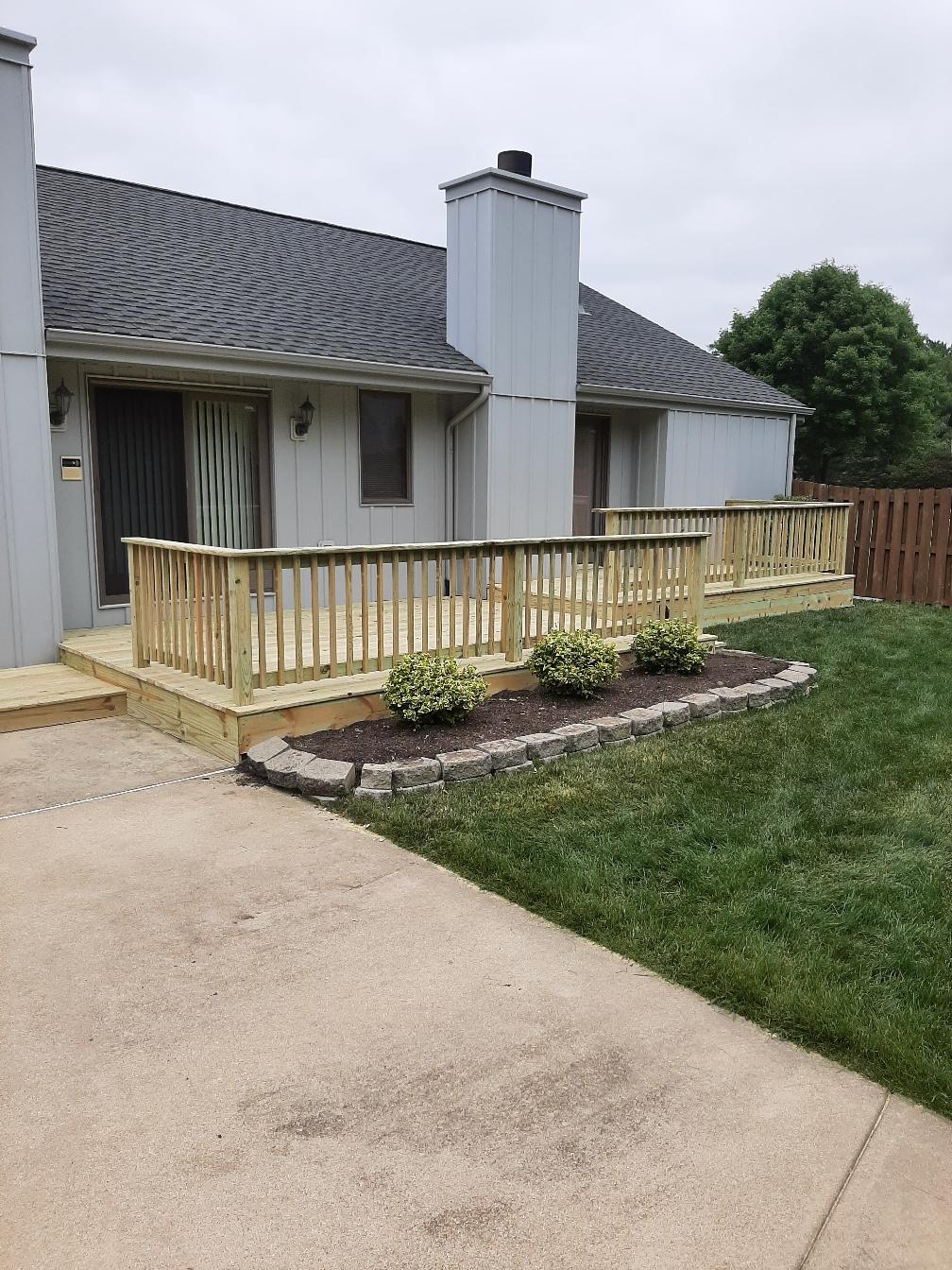 Custom residential pressure-treated wood deck with wood safety railings built alongside a grey siding house by Precision Exterior Inc.