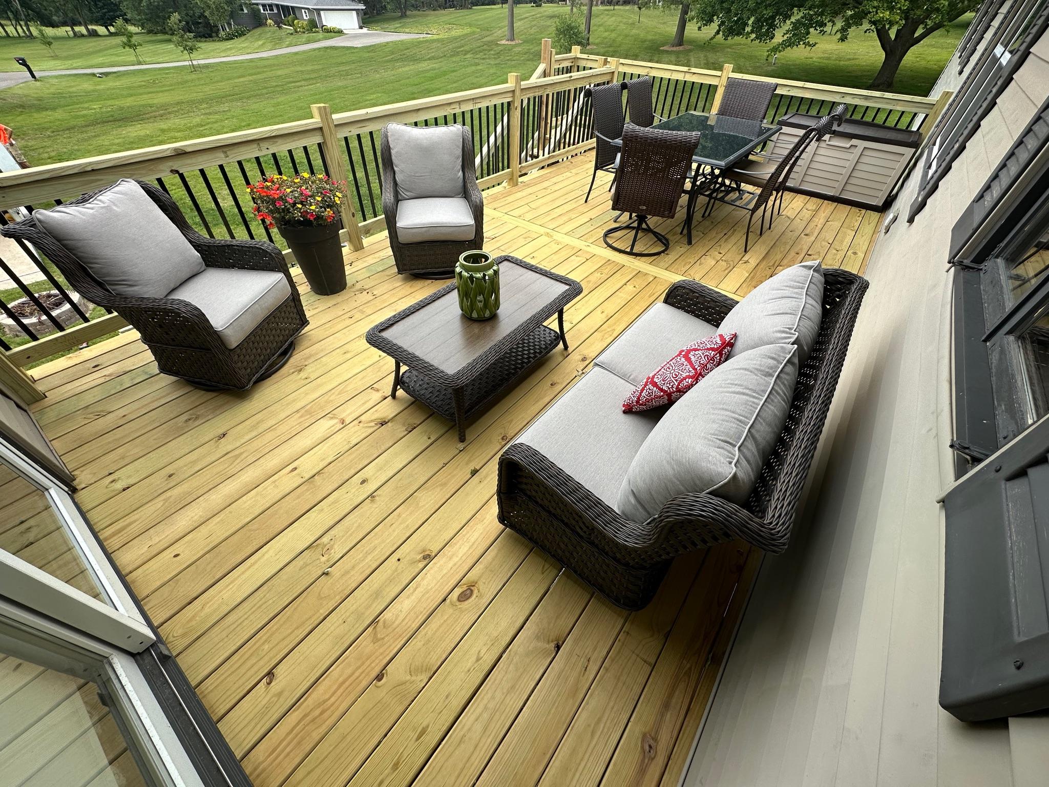 Premium custom wood deck installation with sleek black metal spindles and outdoor lounge furniture, built by Precision Exterior Inc. in Lena, IL.