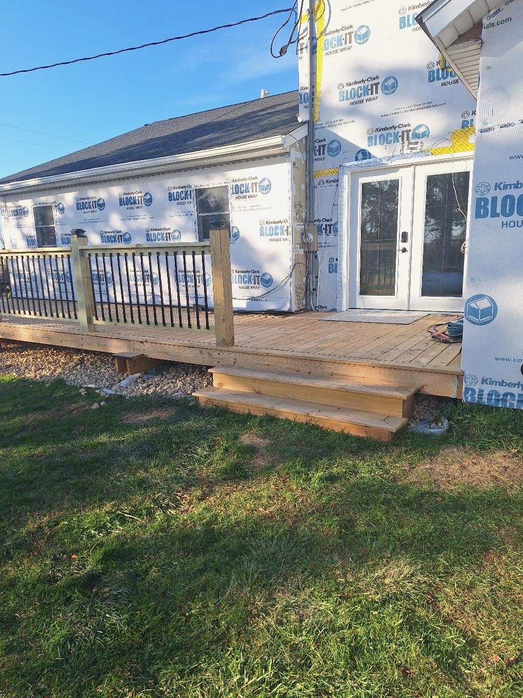 Custom pressure-treated wood deck construction featuring black metal spindles and wooden railing posts by Precision Exterior Inc.