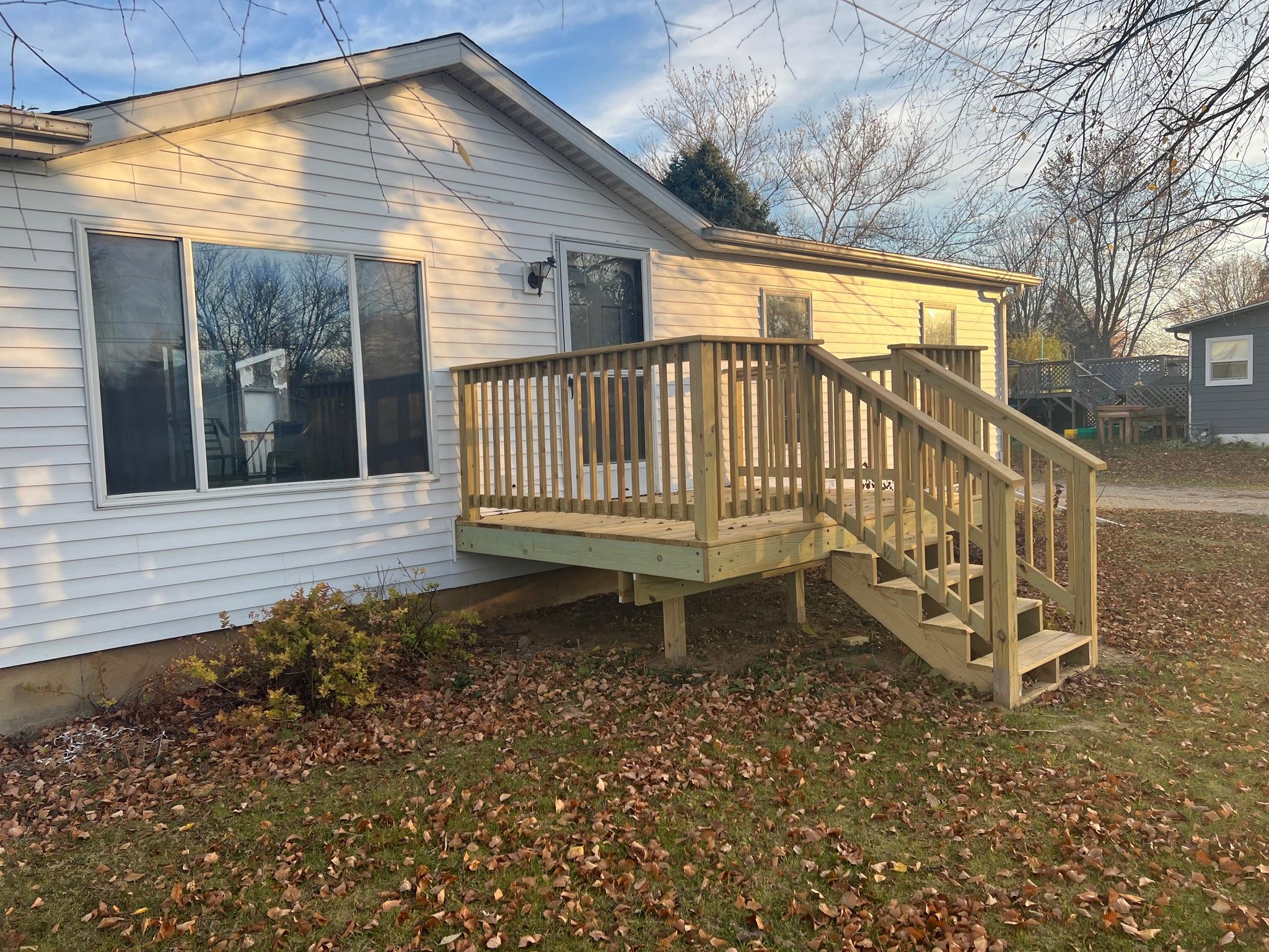 Custom wood porch deck and safety staircase built by Precision Exterior Inc. on a white house in Lena, IL.