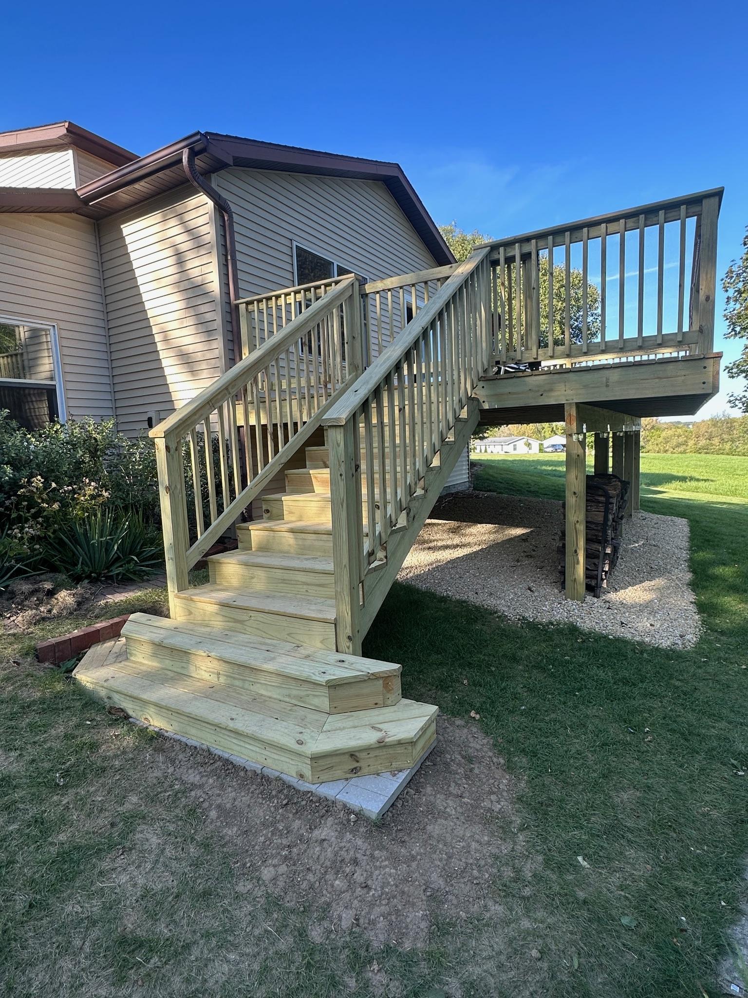 Elevated backyard pressure-treated wood deck with stairs and safety railings built by Precision Exterior Inc.