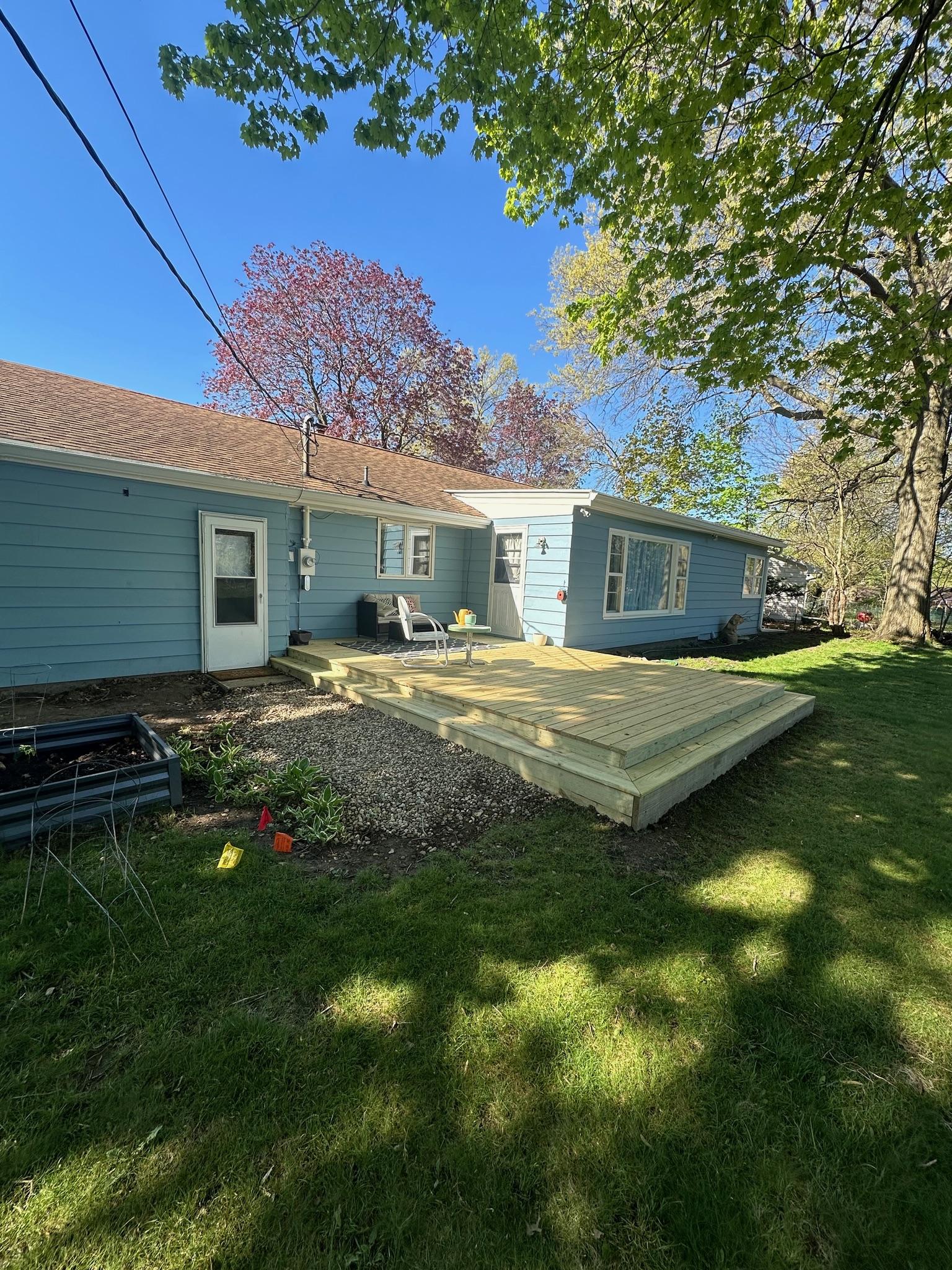 Custom ground-level wood platform deck and wrap-around steps built by Precision Exterior Inc. for a residential backyard in Lena, IL.