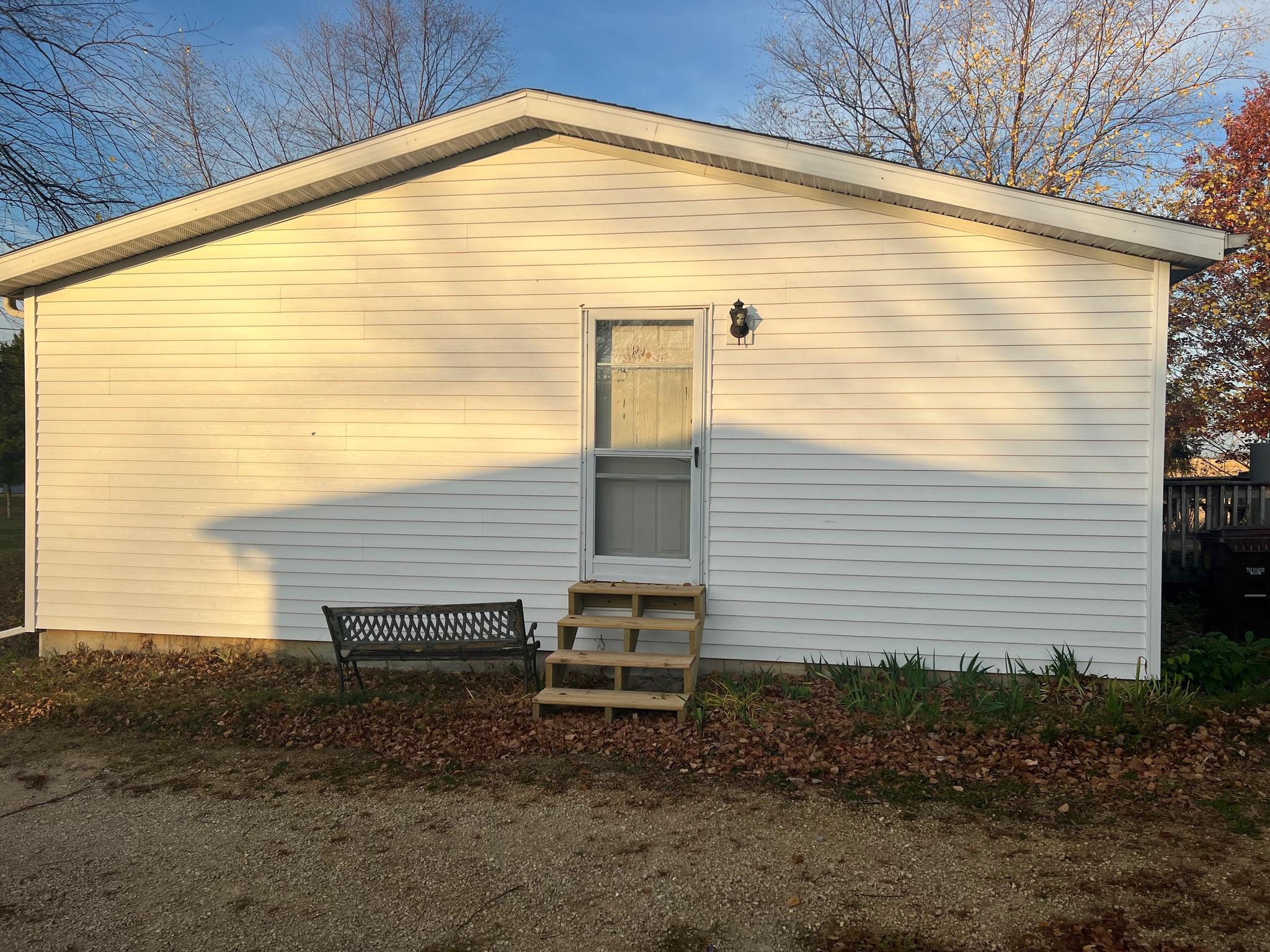 Custom pressure-treated wood exterior stairs built for a home with white vinyl siding by Precision Exterior Inc.