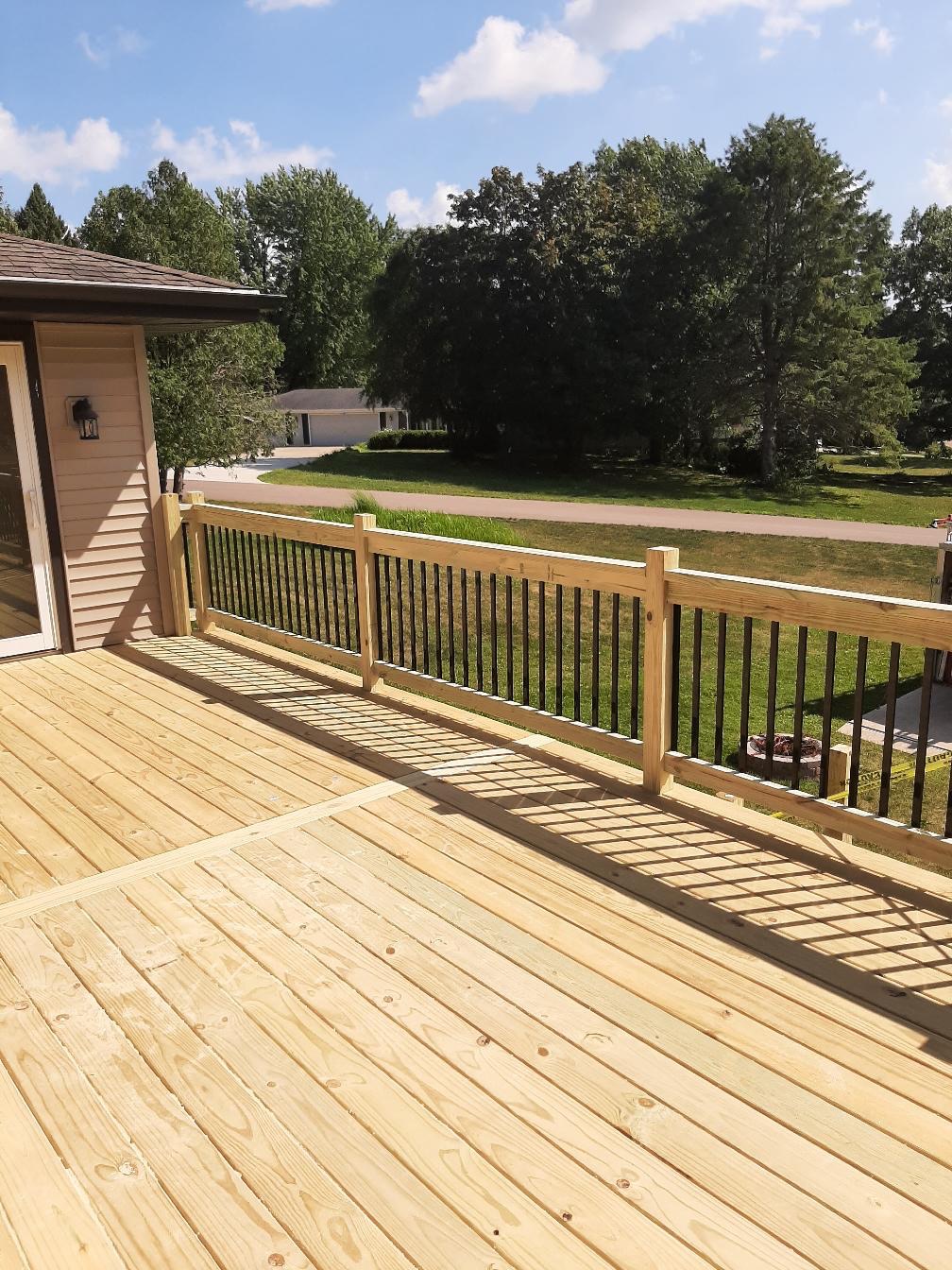 Custom elevated residential wood deck featuring a hybrid railing system with wood frames and black metal balusters, built by Precision Exterior Inc.