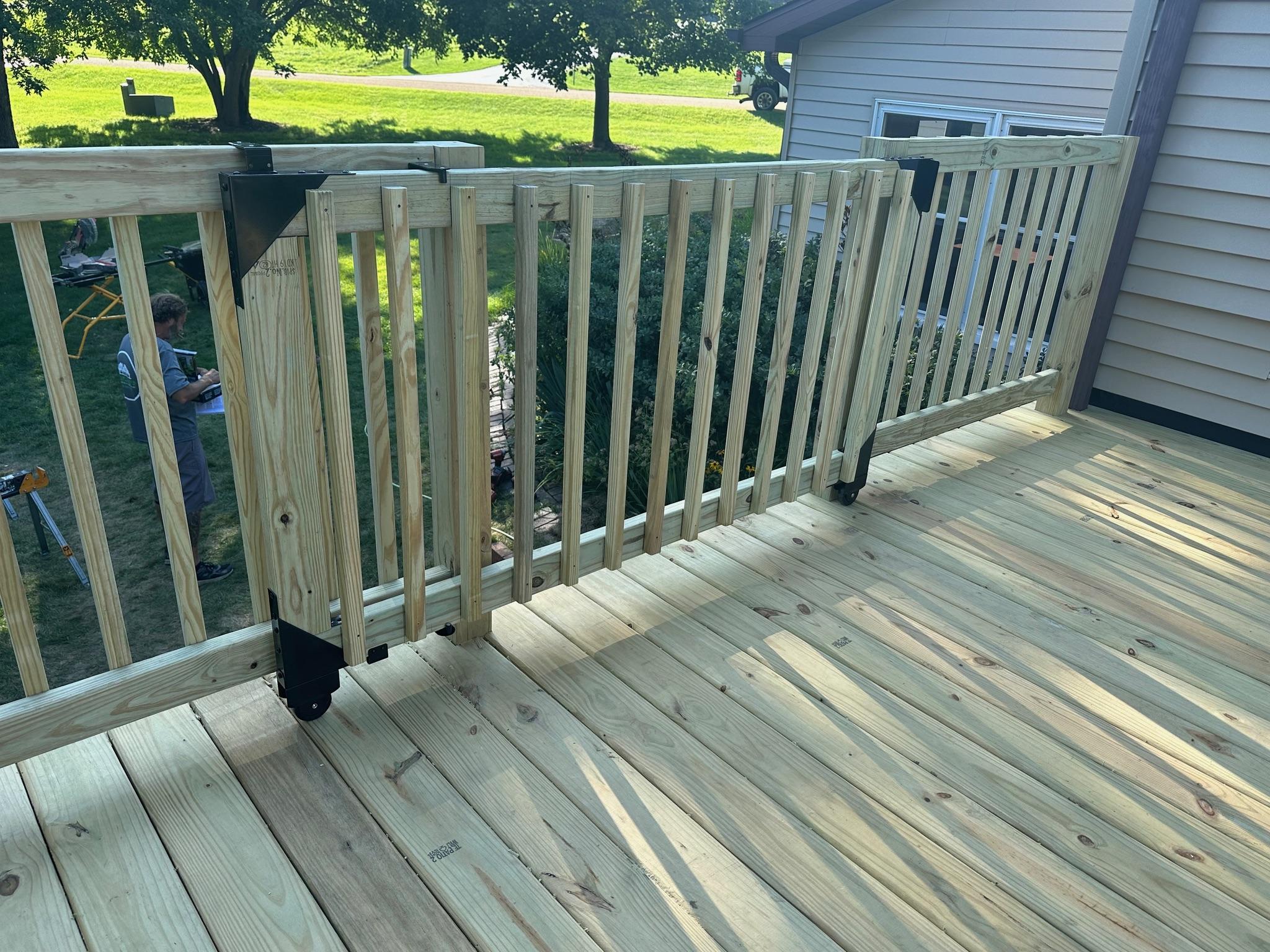 Custom pressure-treated wood deck installation showcasing an integrated wooden safety gate with railings by Precision Exterior Inc.