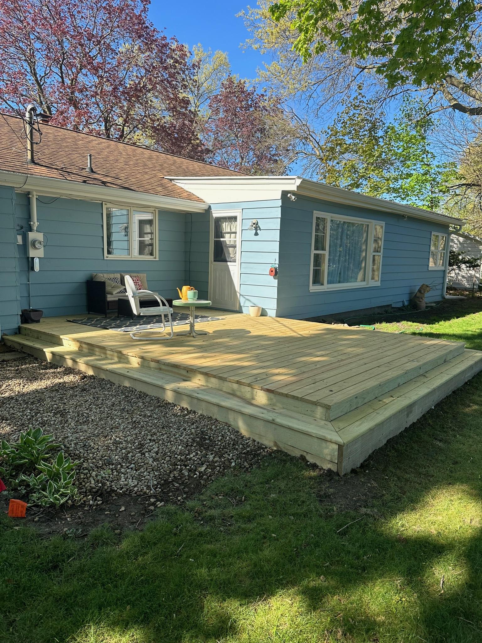 Custom low-profile pressure-treated wood deck built by Precision Exterior Inc. on a blue residential home in Lena, IL.