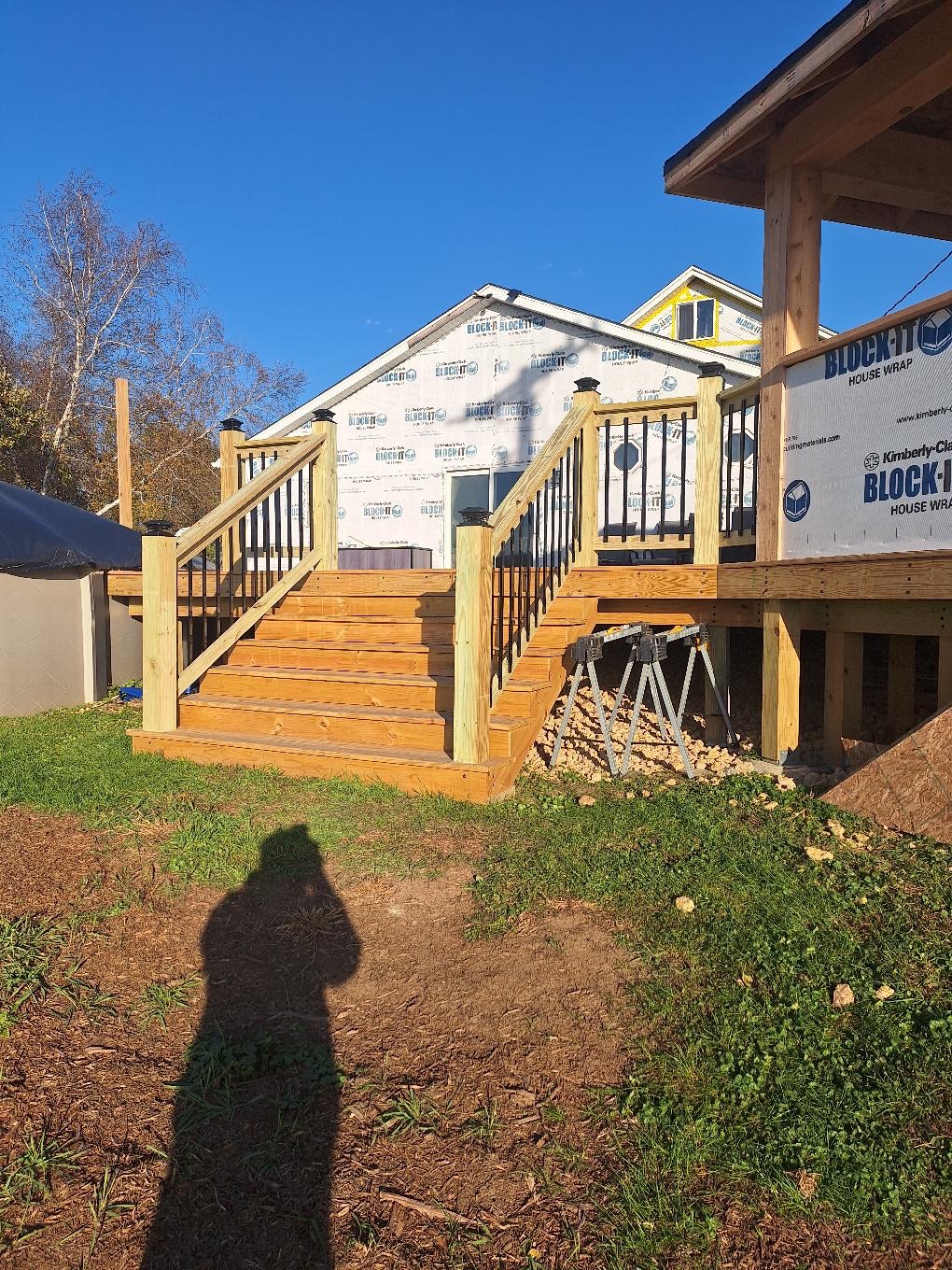 Custom pressure-treated wood deck stairs with wood posts and black metal baluster railings under construction by Precision Exterior Inc.