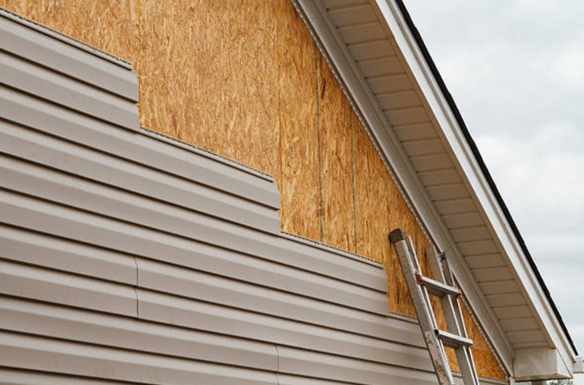 New horizontal siding panels being lined up on a house wall.