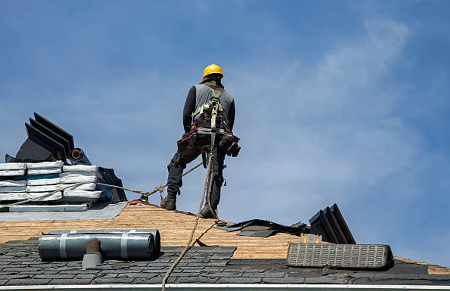 Professional roofer installing new shingles on a residential rooftop.