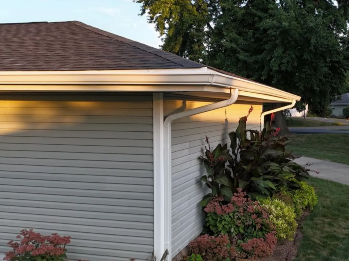Technician installing seamless aluminum gutter system on residential roof by Precision Exteriors Inc