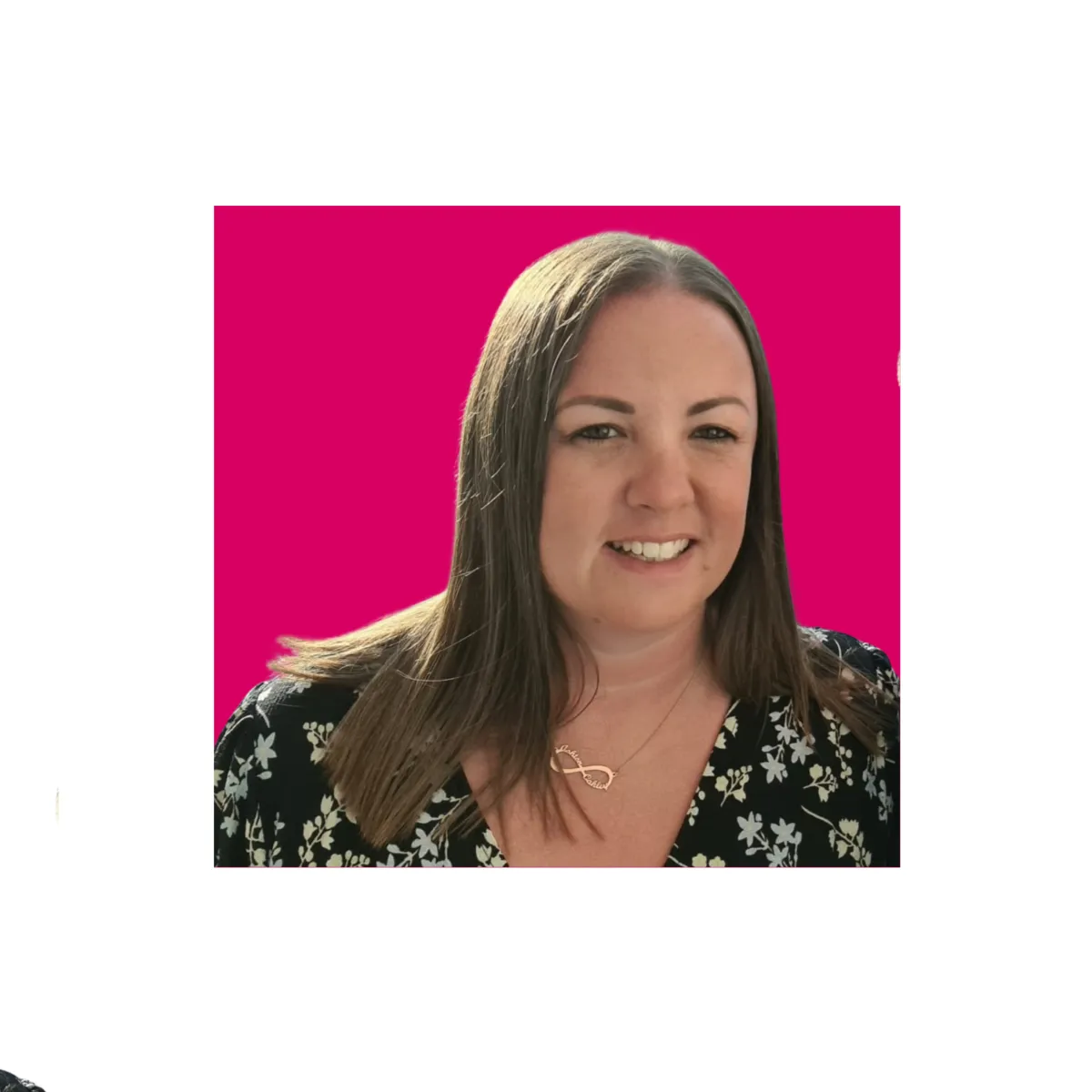 Lad with brunette hair looking at the camera and smiling with a pink background.