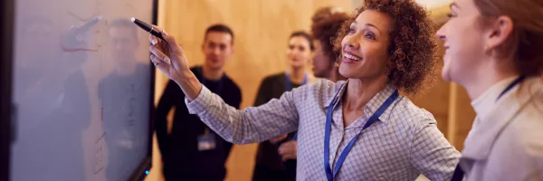 Female staff member training apprentice showing working on a white board