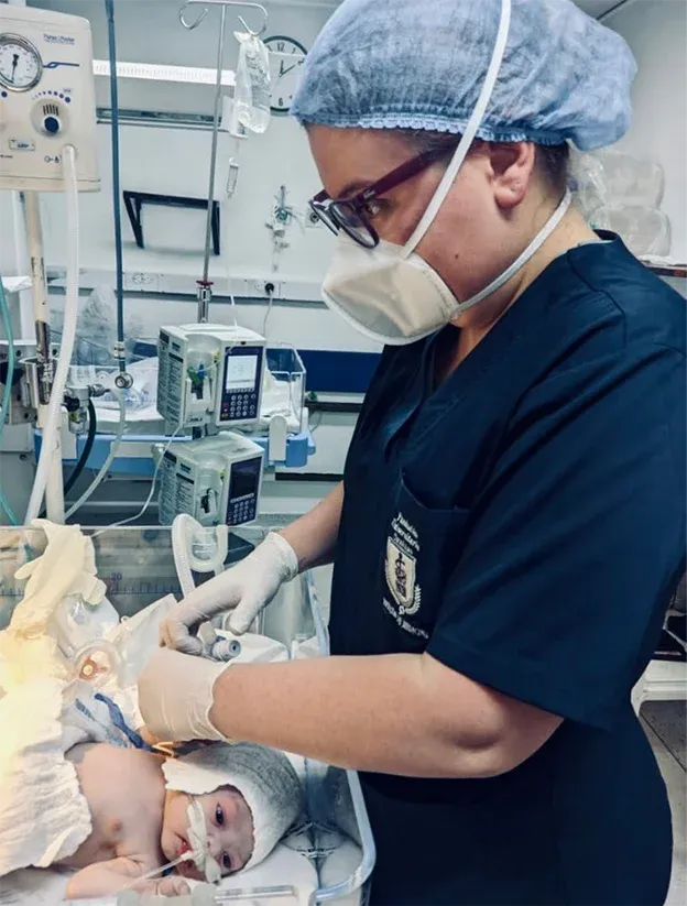 Dra. Verónica Villa atendiendo a un recién nacido en una incubadora hospitalaria.