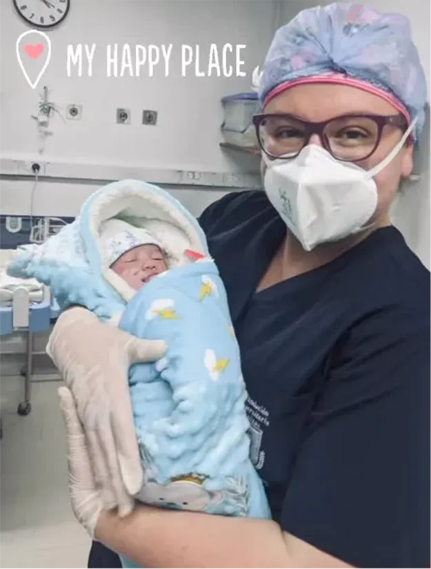 Dra. Verónica Villa sosteniendo a un recién nacido envuelto en una manta en un entorno hospitalario.