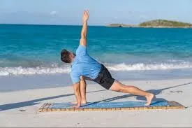 man on a beach stretching and doing yoga