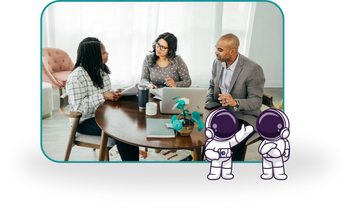 A diverse group of three people discuss around a table with a laptop.
