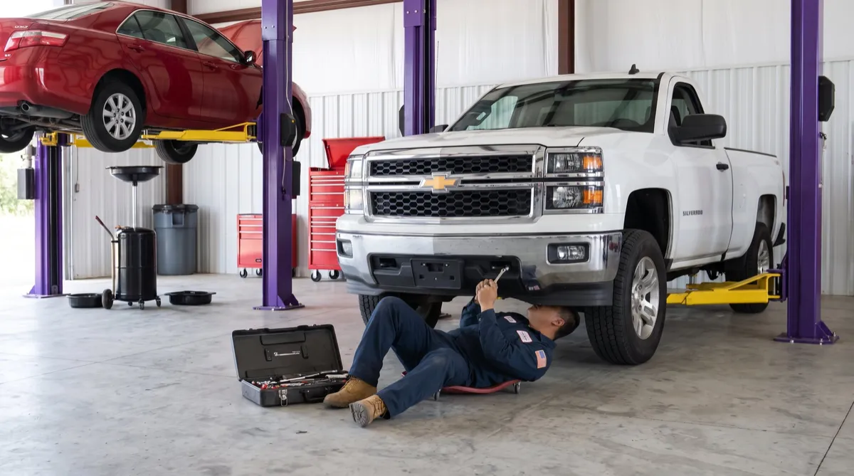 Gus’s Auto Repair mechanic working under a pickup truck