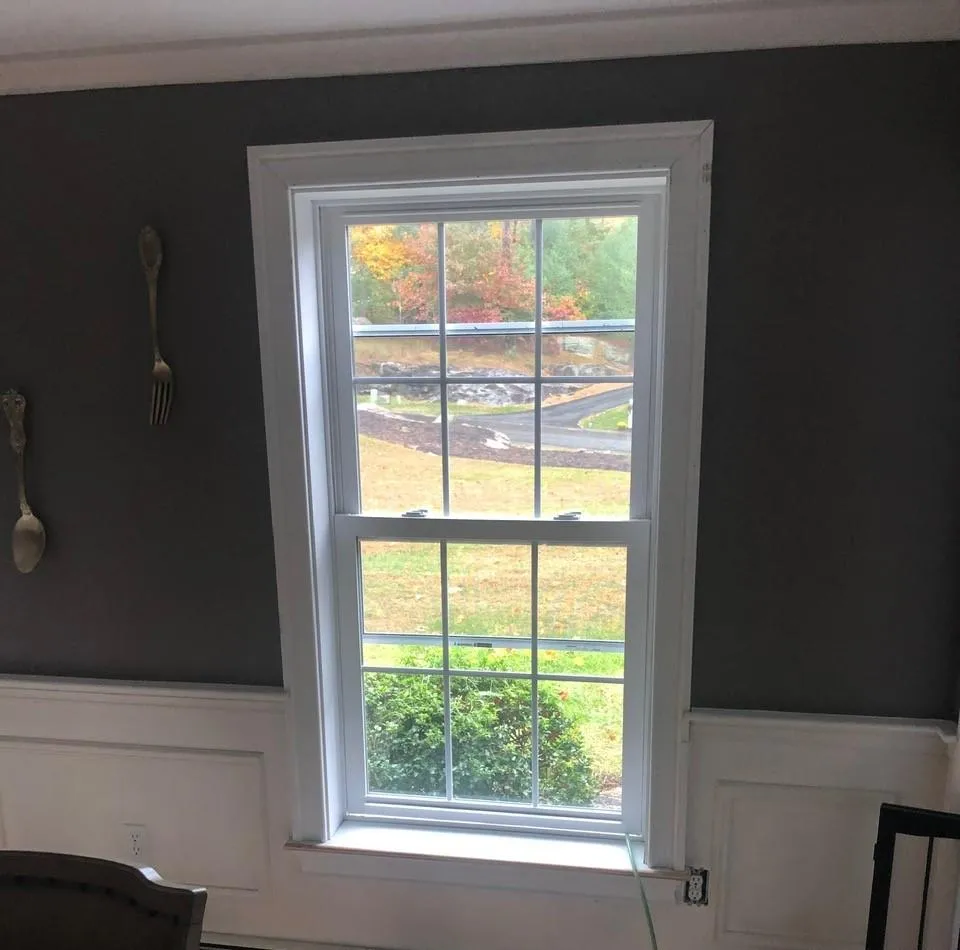 New energy-efficient window installation by McCarthy Exteriors LLC inside a New Hampshire home with white trim and gray walls