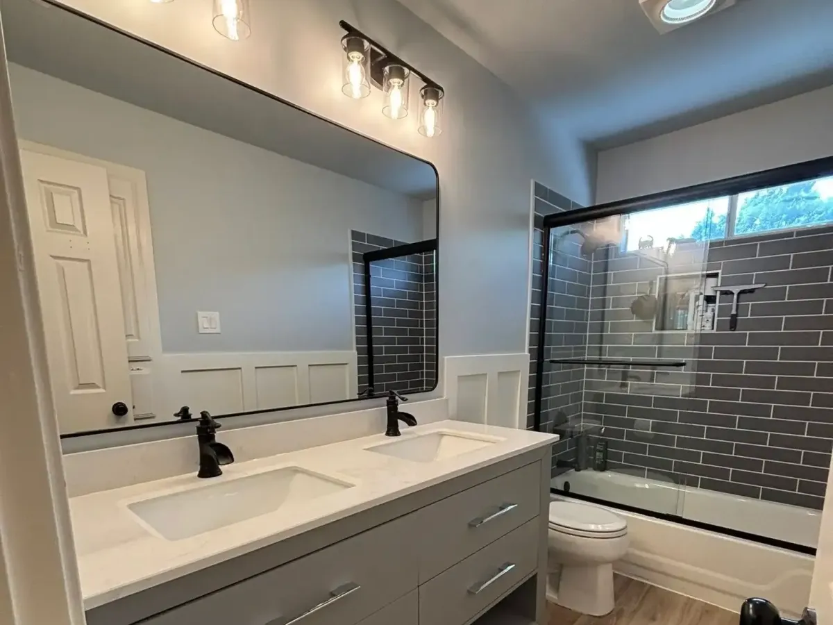 Modern Arlington, TX bathroom with glass shower, quartz vanity, marble floors, recessed lighting, and large windows.
