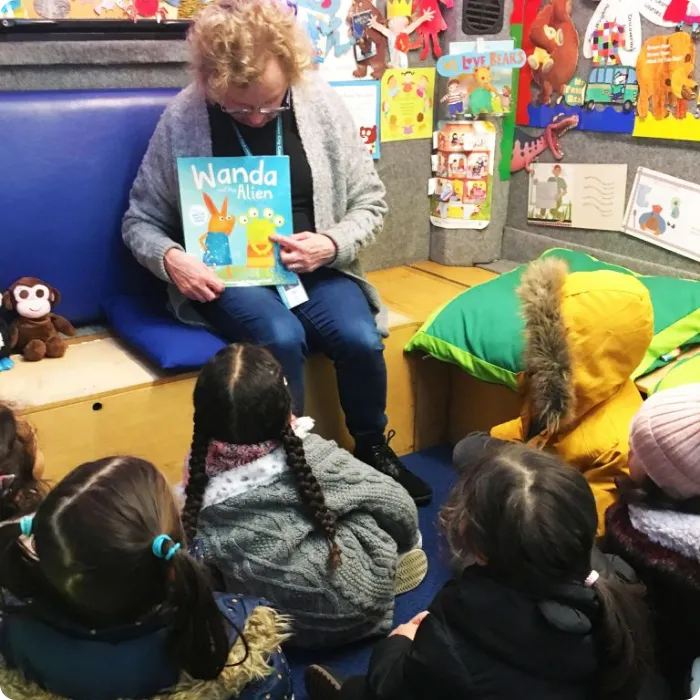 Teacher reading storybook aloud to engaged preschoolers at Little Companions Leicester