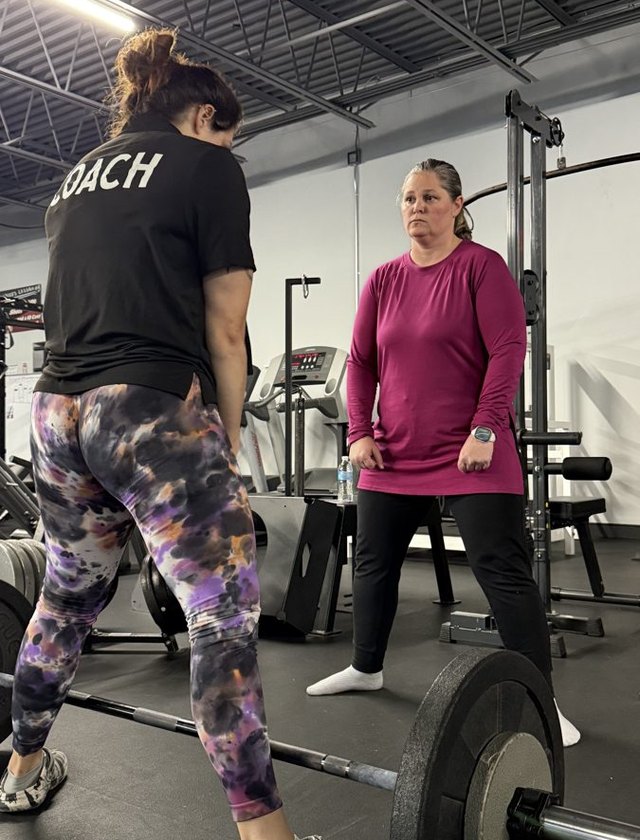 A coach walking a client through a deadlift setup
