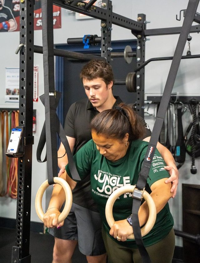 A coach assisting a client on the rings