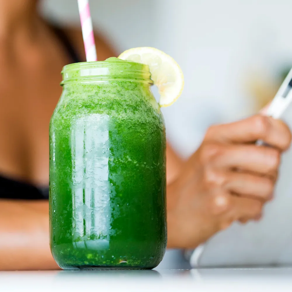 An image of a green smoothie with woman working on the background