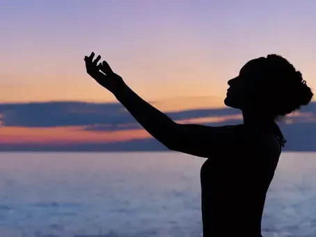 A woman doing meditation with arms raised towards the sky.