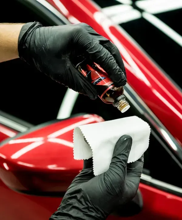 Applying ceramic coating to red car with microfiber cloth