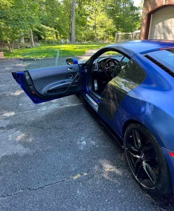 Audi R8 V10 interior with open door and matte blue wrap.