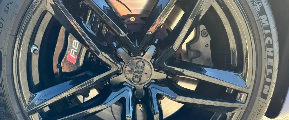 Close-up view of an Audi R8 alloy wheel and high-performance brake system with Michelin tire.