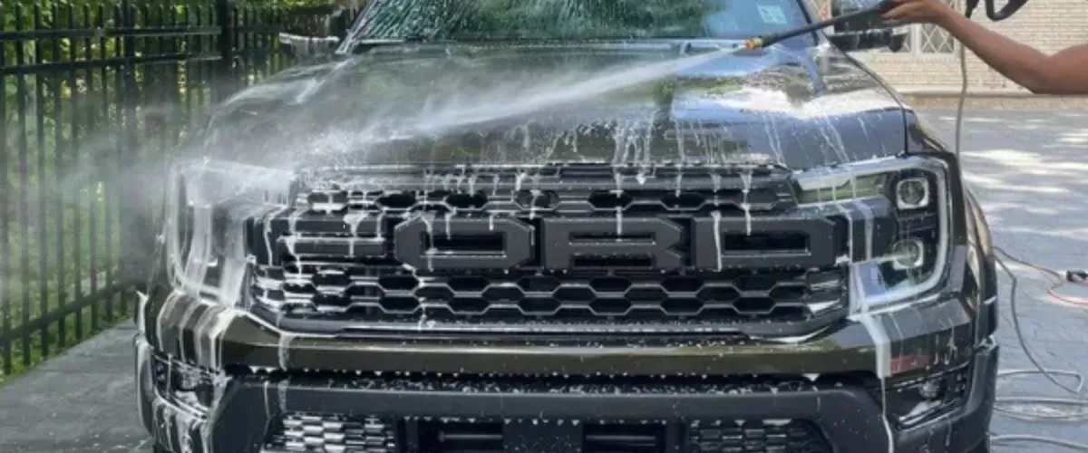 Ford Raptor truck being pressure washed during an exterior detailing service." 