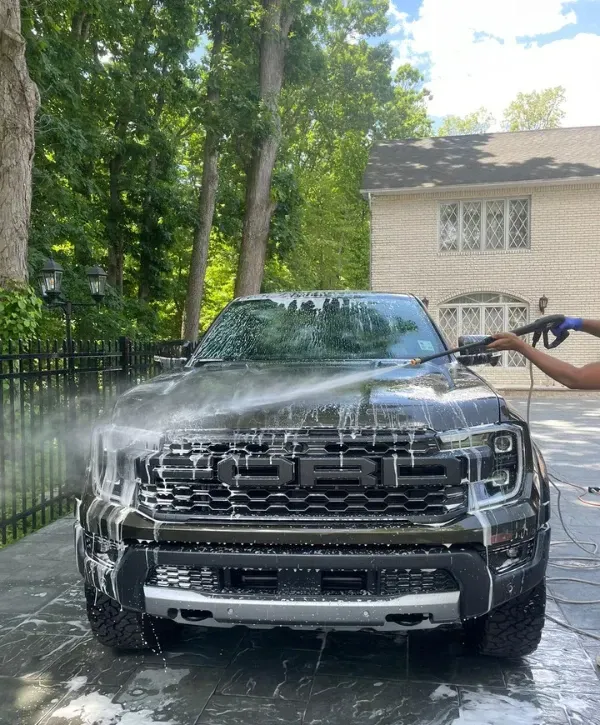 Professional exterior detailing of a Ford truck with soap and pressure rinsing in a residential driveway.”