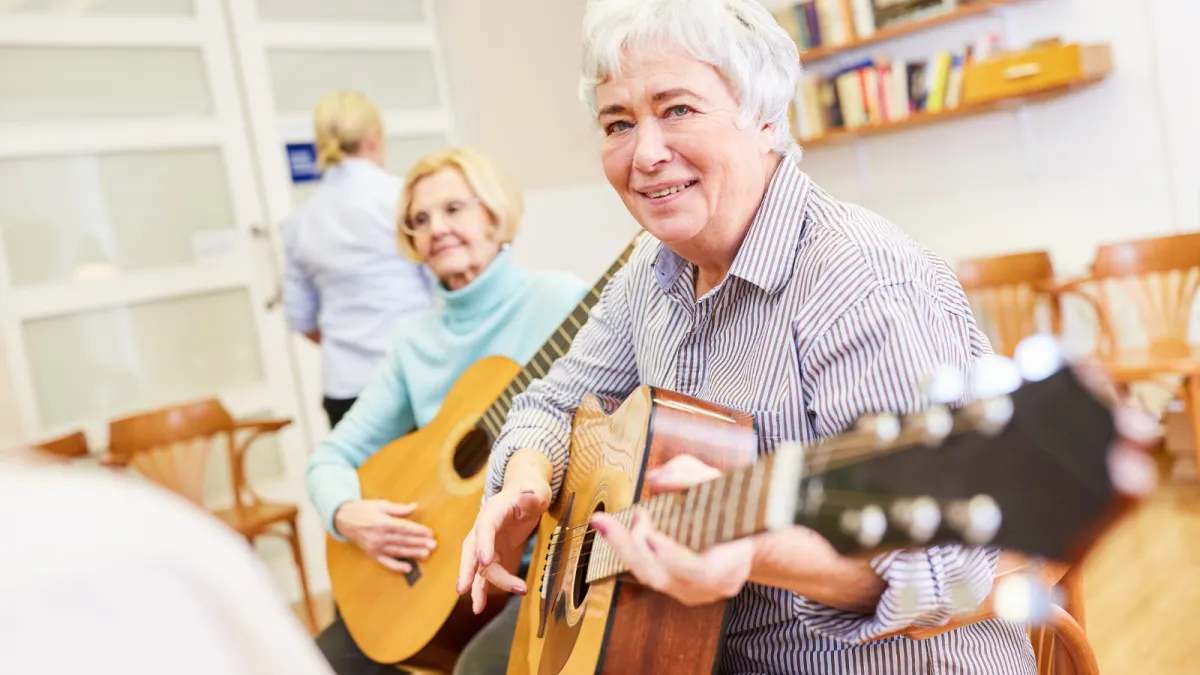 An adult, dressed in a colorful long sleeve and eyeglasses, sits attentively at a sleek digital keyboard, their fingers moving gracefully over the keys. The soft glow of a tilt light bathes the scene, casting an inviting, warm ambiance around them.