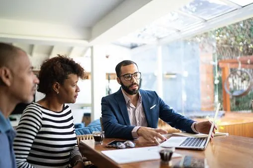 Realtor siting at a table with husband and wife client communicating options