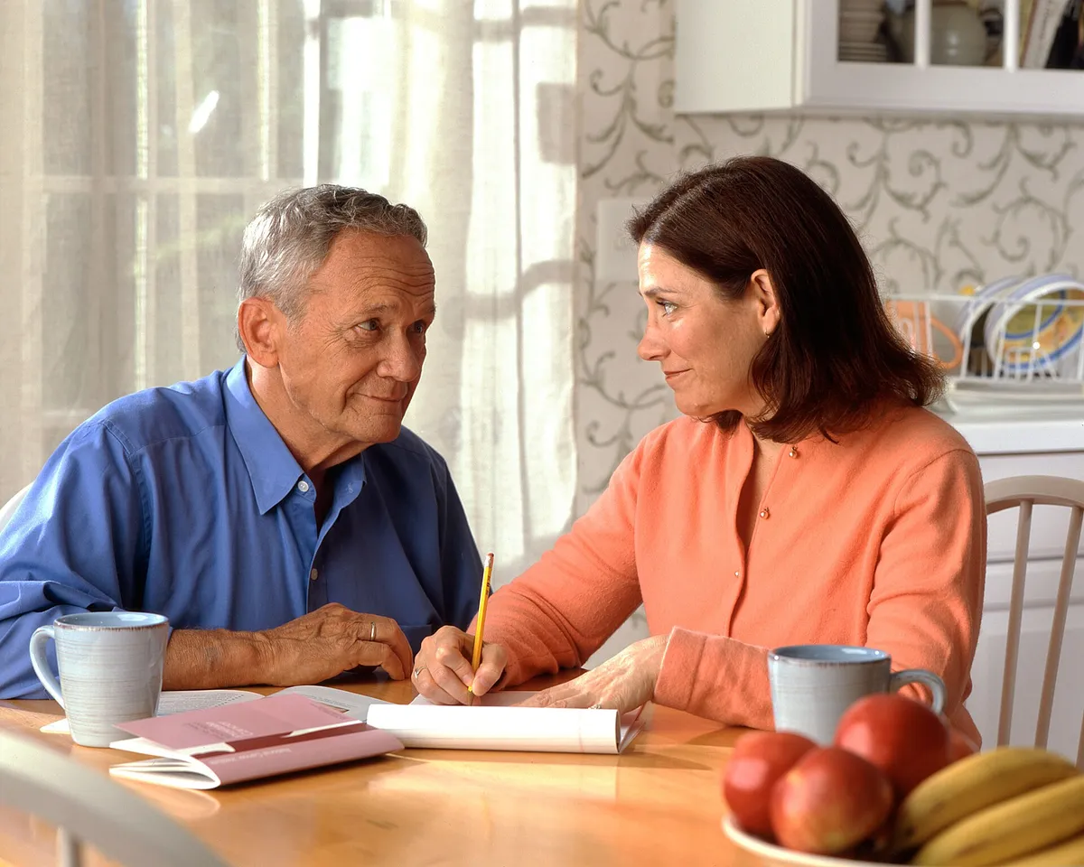 Couple reviewing paperwork together at a kitchen table — a realistic photo for "If You're Sidelined for 90 Days, Who Keeps Your Business Rolling?" on income protection for owner-operators.