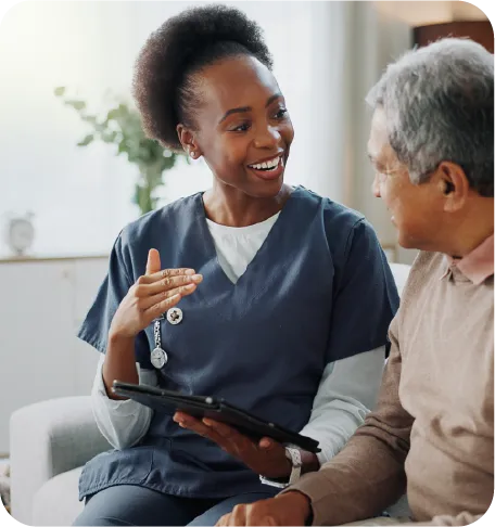 A dark nurse talking to a colored elderly man