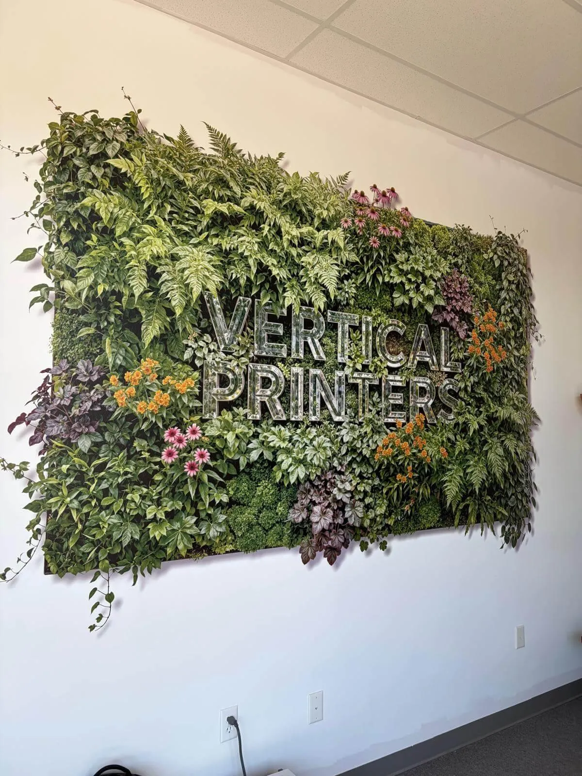 ECMP | A vibrant 3D vertical garden moss and plant wall installation featuring custom metallic "VERTICAL PRINTERS" branding text in a corporate lobby.