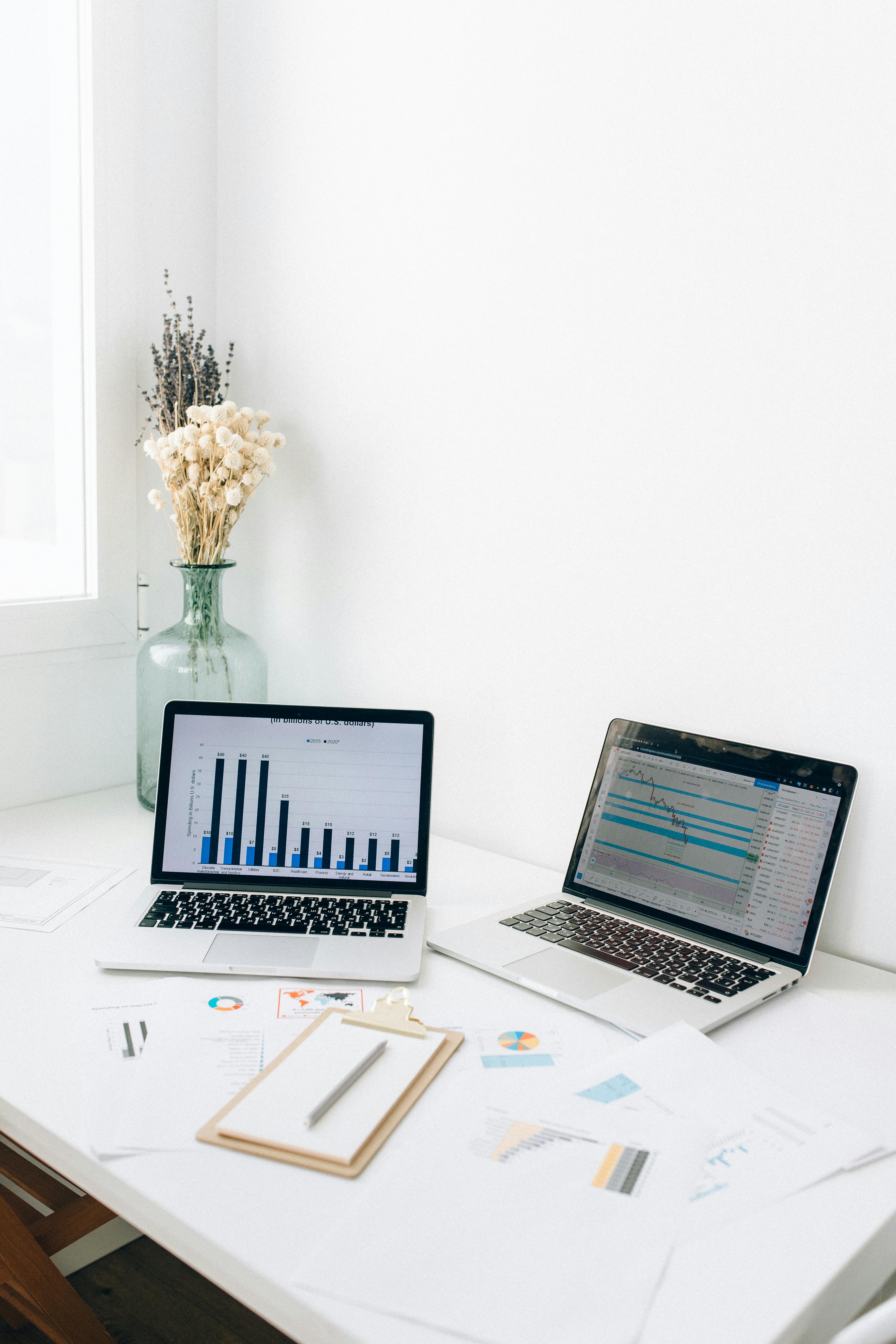 Two laptops displaying analytics dashboards alongside printed reports and charts on a desk, representing effort without full strategic alignment in social media management.