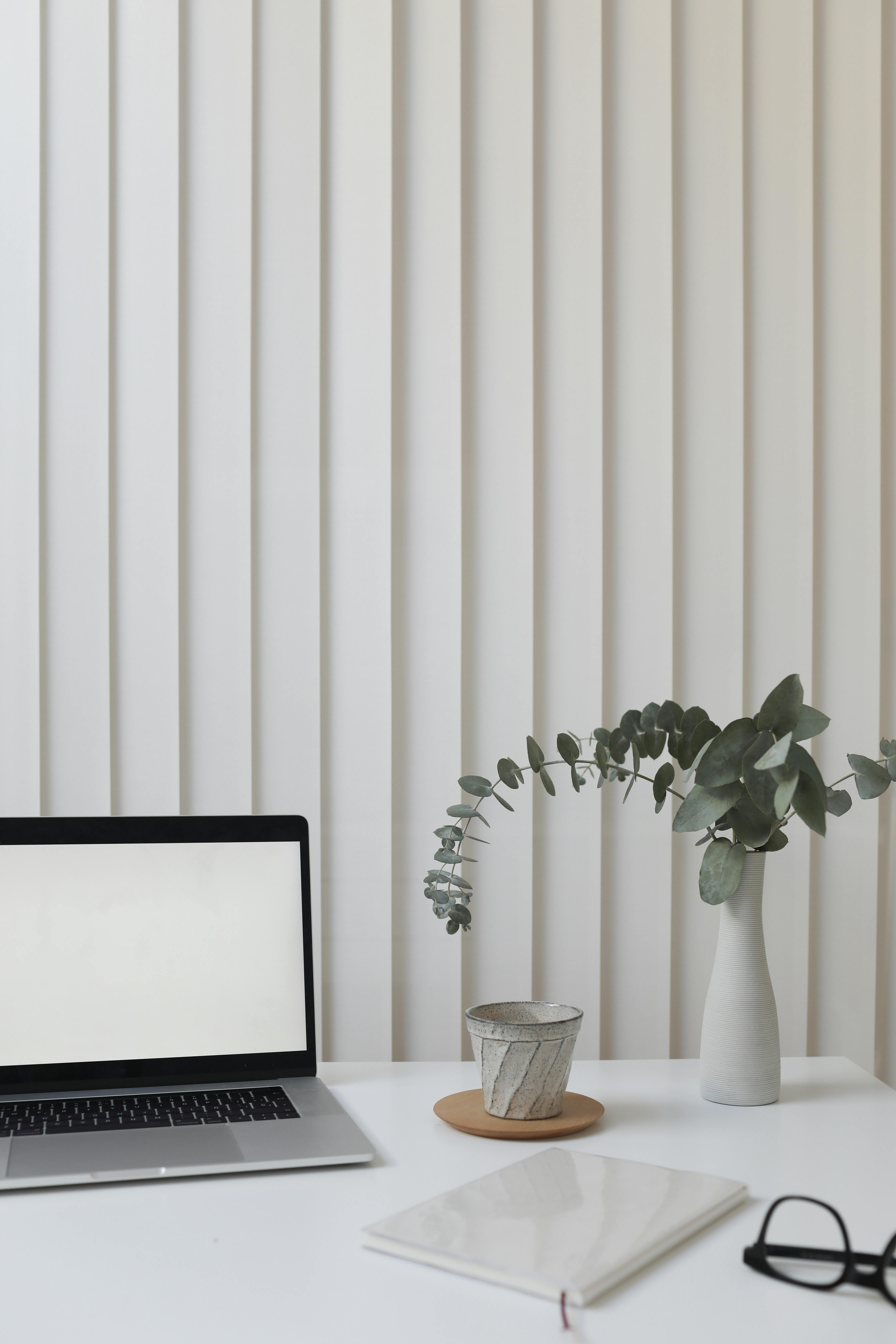 Minimal professional workspace with laptop, notebook and plant, representing structured and reliable brand delivery for UK service providers.